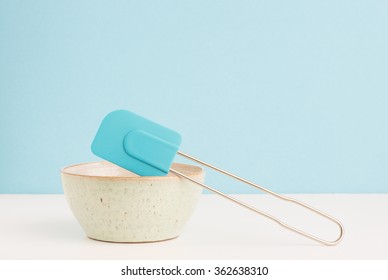 Kitchen Bowl And Dough Scraper On Table. Concept Of Baking, Cooking And Food Preparation. Clean Blue Background With Copyspace.