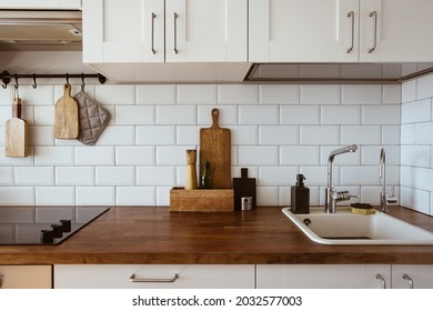 Kitchen brass utensils, chef accessories. Hanging kitchen with white tiles wall and wood tabletop.Kitchen background
