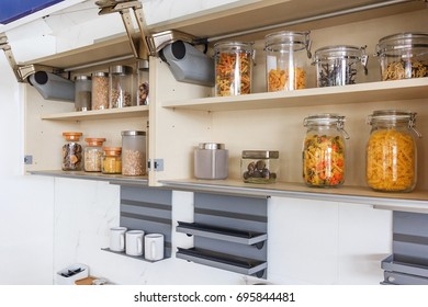 Kitchen cabinet with opened fronts with kitchen bench shelves with various food ingredients on white background