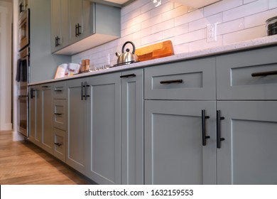 Kitchen cabinets with white countertop black handles and tile backsplash - Shutterstock ID 1632159553