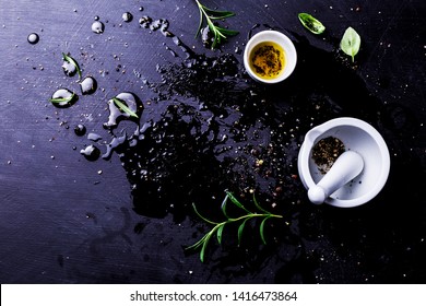 Kitchen And Cooking - Dark, Moody, Messy Background. Olive Oil, Mortar And Herbs On Black Wet Counter. Captured From Above (top View, Flat Lay), Free Copy (text) Space.