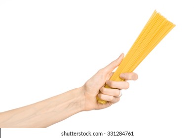 Kitchen and Cooking topic: human hand holding a pile of dry yellow spaghetti isolated on white background in studio