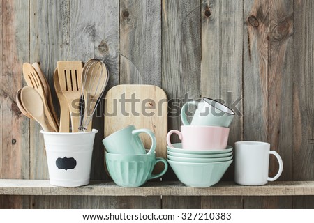 Kitchen cooking utensils in ceramic storage pot on a shelf on a rustic wooden wall