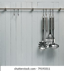 Kitchen Cooking Utensils On Steel Rack; Steel Spatulas Etc Against Rustic Wooden Wall; Good Copy-space