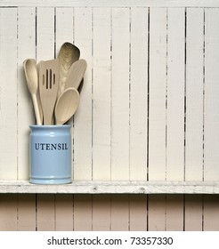 Kitchen Cooking Utensils; Wooden Spatulas Etc In China Storage Pot; On Wooden Shelf Against Rustic Kitchen Wall; Excellent Copy Space Over Wall Area