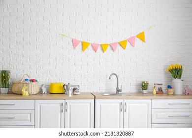 Kitchen Counter With Different Utensils And Easter Decor Near White Brick Wall