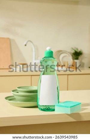 A kitchen counter with stack of green plates, a sponge, and dishwashing liquid in focus, set under soft lighting to reflect a peaceful domestic moment. Unlabeled for design