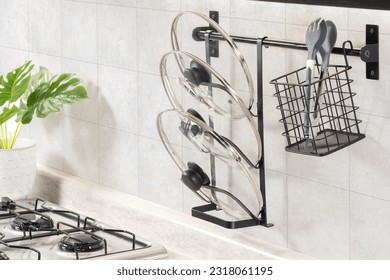 a kitchen counter with two stainless steel cooking utensils and multiple metal cooking pans hanging from a wall