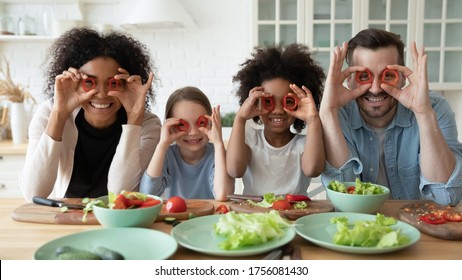 In Kitchen Couple And Multi Racial Daughters Prepare Vegetable Salad Having Fun Make Funny Faces Cover Eyes With Red Paprika Circles Looking Like Eyewear, Binoculars Shape, Cookery, Family Joy Concept