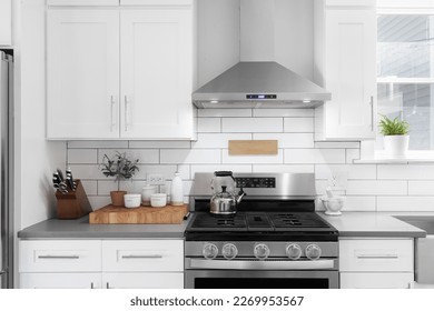 A kitchen detail shot with white cabinets, stainless steel appliances, granite countertops, and a subway tile backsplash. - Shutterstock ID 2269953567