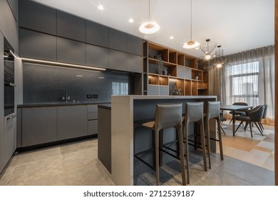 The kitchen and dining area showcases a functional design with modern furnishings and ample storage. Natural light fills the space through large windows, creating an inviting atmosphere.