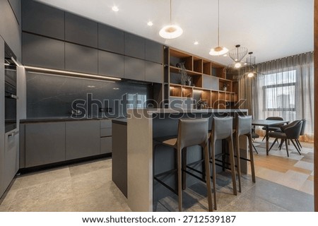 The kitchen and dining area showcases a functional design with modern furnishings and ample storage. Natural light fills the space through large windows, creating an inviting atmosphere.