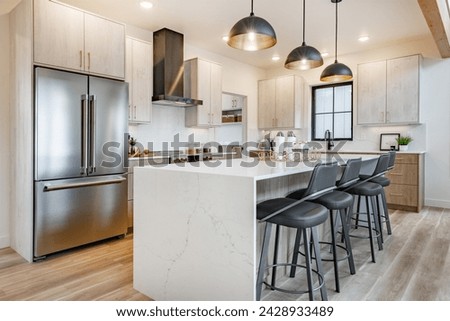 Kitchen and dining room interior with light colors aqua blue hardwood flooring grey chairs bar stools kitchen island stainless appliances and large windows