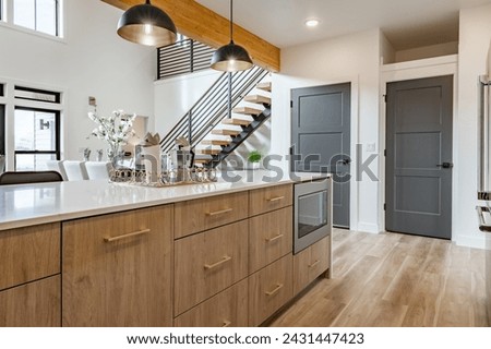 Kitchen and dining room interior with light colors of aqua blue turquoise large exposed staircase with wrought iron hardwood floors bar stools kitchen island stainless appliances open concept bright