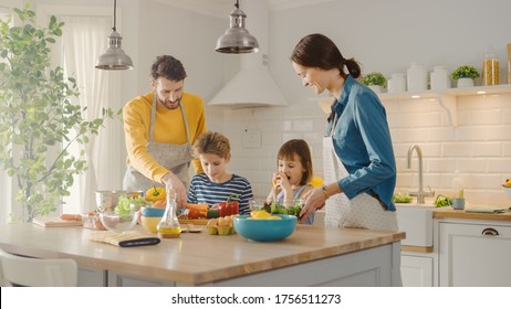 In Kitchen: Family of Four Cooking Together Healthy Dinner. Mother, Father, Little Boy and Girl, Preparing Salads, Washing and Cutting Vegetables. Cute Children Helping their Beautiful Caring Parents - Powered by Shutterstock