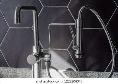 Kitchen Faucet And Sprayer With Natural Morning Light On Black Hexagon Tile Background 