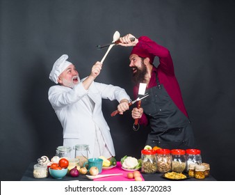 Kitchen fight. Two chefs on kitchen. Kitchen. Cooking. Beared chef man. Delicious food. Male chef in uniform. Chef, cook or baker.