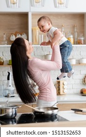 Kitchen Fun. Mommy Lifting Her Son Up In Air, Cooking Lunch Together