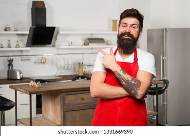 Kitchen Furniture Store. Cooking In New Kitchen. Need Culinary Inspiration. Weekend Begins From Tasty Breakfast. How To Turn Cooking At Home Into Habit. Man Bearded Hipster Red Apron Stand In Kitchen.