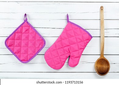 Kitchen Glove, Pot Holder And Wooden Ladle On White Wooden Planks