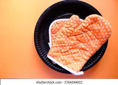 Kitchen Gloves On Orange Background Top Down.