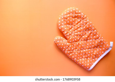 Kitchen Gloves On Orange Background Top Down.