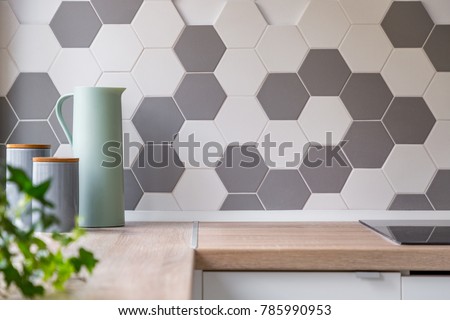 Kitchen with grey and white honeycomb wall tiles and wooden worktop,