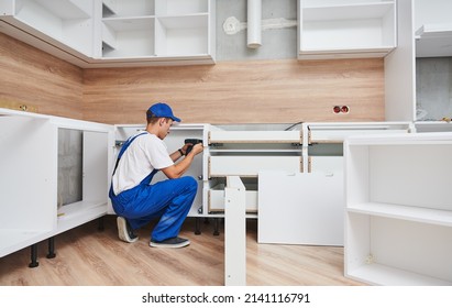 kitchen installation. Worker assembling furniture - Shutterstock ID 2141116791