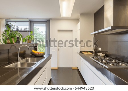 Kitchen interior with the aisle between two worktops, silver sink and amenities