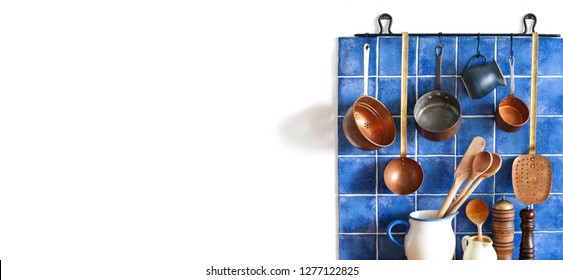 Kitchen Interior With Vintage Copper Utensils. Old Style Cookware Kitchenware Set. Pots, Kitchen Spoon, Skimmer Hanging On Blue Tile Wall. Copy Space, White Background.