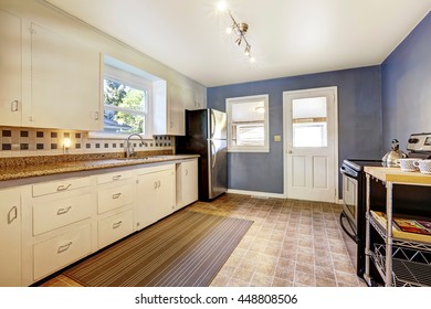 Kitchen Interior With White Cabinets, Tile Floor And Bright Navy Walls