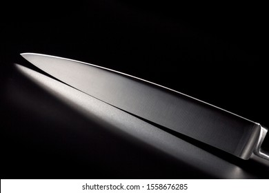 Kitchen knife with a white handle on a black background. A sharp blade of a knife.