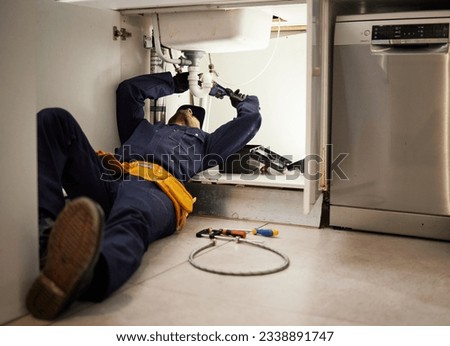 Kitchen, maintenance and renovation with a plumber on the floor of a home to fix a leak, issue or problem. Plumbing, repair and tools with a handyman or contractor working on a pipeline in a house