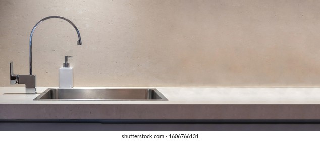 Kitchen modern interior detail. Kitchen sink and water tap front view, Stone beige color countertop banner, copy space