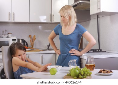  in the kitchen. mother scolding a child. a child refuses to eat, mom makes daughter eat healthy. mom and daughter are having Breakfast, the baby won't eat. quarrels, conflicts in the family