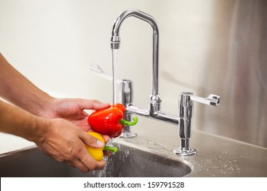 Kitchen Porter Washing Vegetable In Professional Kitchen