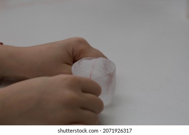 In A Kitchen Science Experiment A Child Attempts To Lift An Ice Cube With A Thin Red Thread.