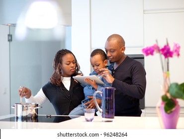 Kitchen Setting With Young Black Family Playing With A Tablet Pc.