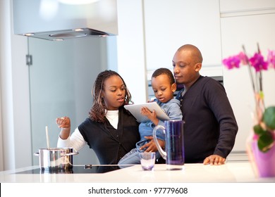 Kitchen Setting With Young Black Family Playing With A Tablet Pc.