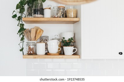 Kitchen shelves with various white ceramic and glass jars. Open shelves in the kitchen. Kitchen interior ideas. Eco friendly kitchen, zero waste home concept