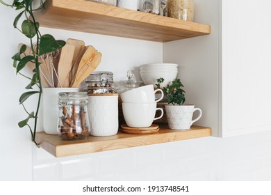 Kitchen shelves with various white ceramic and glass jars. Open shelves in the kitchen. Kitchen interior ideas. Eco friendly kitchen, zero waste home concept
