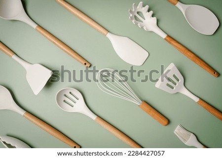 Kitchen silicone utensils for cooking tools on green background, top view, flat lay. Kitchenware collection with copy space. Cooking background.