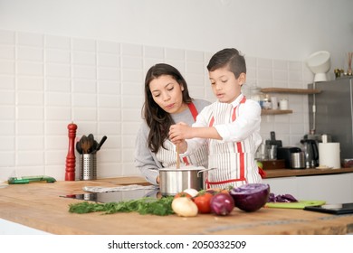 In The Kitchen: A Single-parent Family Cooking Pasta Together. Mother And Son Stirring Pasta In The Pot. Children Helping Parents. Healthy Eating.