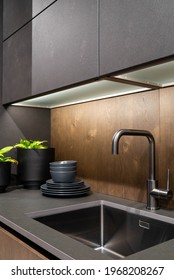 Kitchen sink area with plants and stacked dishes. Gray concrete and wood loft kitchen design.