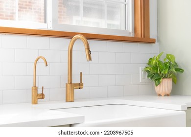 A Kitchen Sink Detail Shot With A Gold Faucet, Apron Sink, Subway Tile Backsplash, And A Light Green Cabinet.