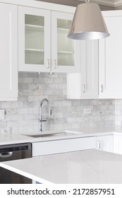 A Kitchen Sink Detail Shot With White Cabinets And A Marble Subway Tile Backsplash.