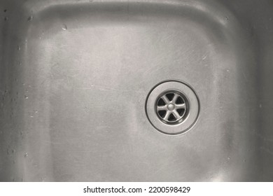 Kitchen Sink, Old Scratched With Drops Of Water. Clean Shiny Old Stainless Steel Kitchen Sink With Drain Hole. Sink Drainage With No Plug