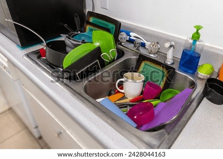 Kitchen sink stacked full of assorted filthy dishes in need of a wash