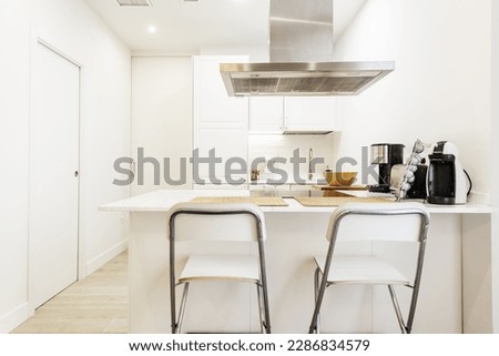 Kitchen with smooth white wood cabinets, built-in appliances, light laminate flooring, island with sintered stone countertop, and white sliding door