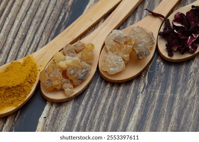 A kitchen studio food shot of various spices (Turmeric, Nutmeg, Hibiscus, Frankincense and Acacia) in a wooden spoons isolated on a wooden background. - Powered by Shutterstock